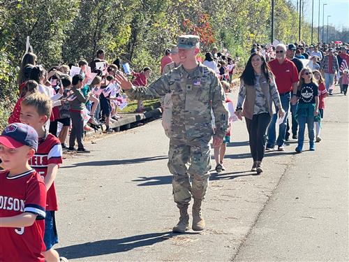 veteran waving while walking through the lineup of students in the Mill Creek Elementary parade